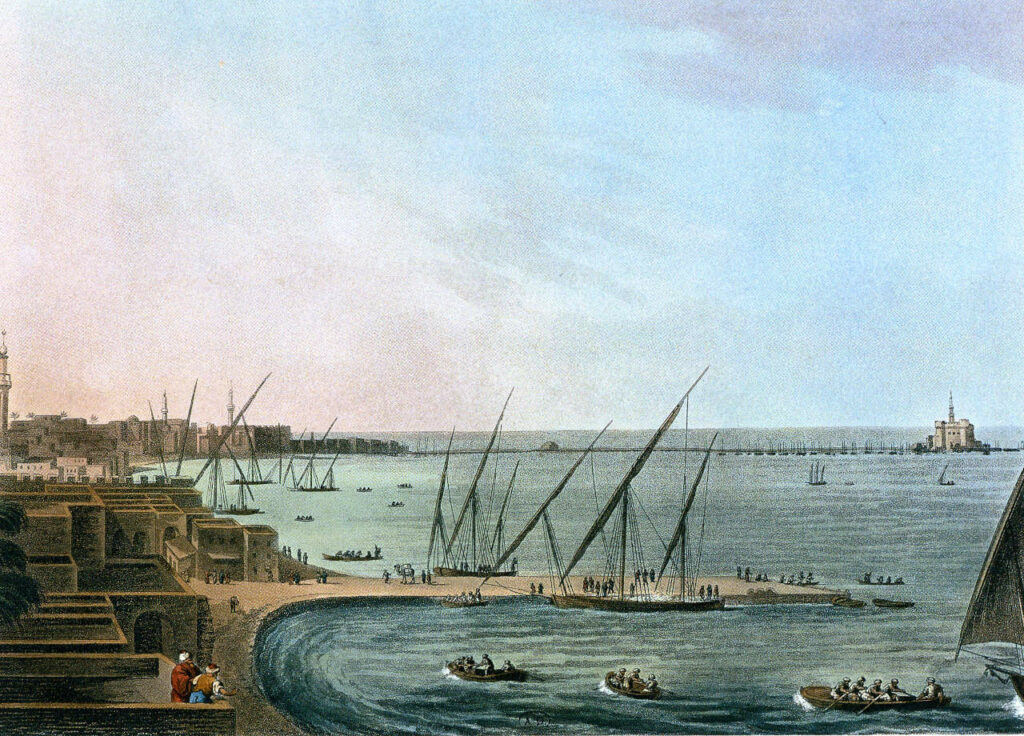 The port of Alexandria shows sand houses along the beach. Boats are involved in shipping and trade. On the far left horizon we see a lighthouse.