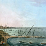 The port of Alexandria shows sand houses along the beach. Boats are involved in shipping and trade. On the far left horizon we see a lighthouse.